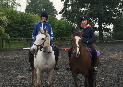 Two young adults riding ponies